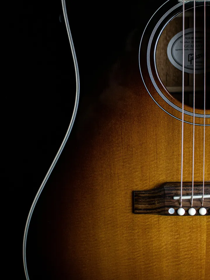 The body of a sunburst acoustic guitar on a black background