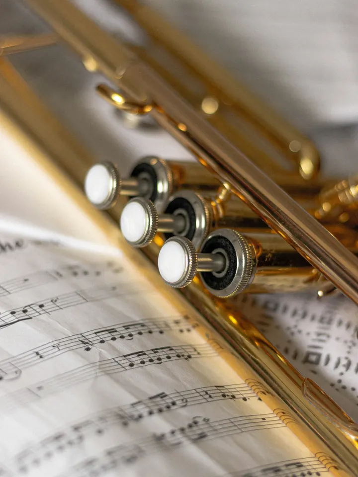 The valves of a brass trumpet resting on sheet music