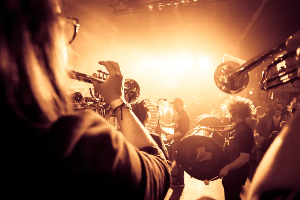 A trumpet player in front of a brightly lit stage and drum kit